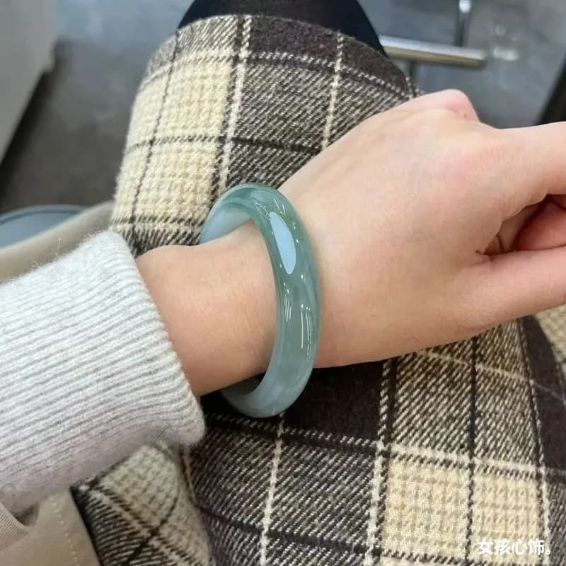 A woman wearing a natural Burmese ice jadeite bracelet in oil green.