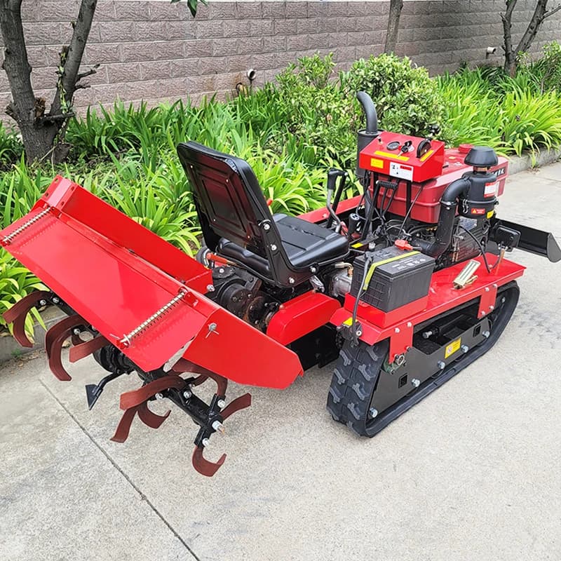 Red heavy-duty crawler tractor with rubber tracks and rear-mounted rotary tiller attachment.