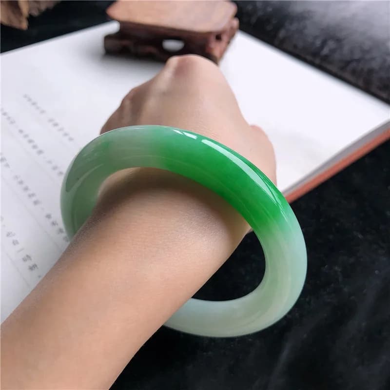 Genuine light green ice-waxy Burmese jadeite round bar bracelet worn on a wrist.