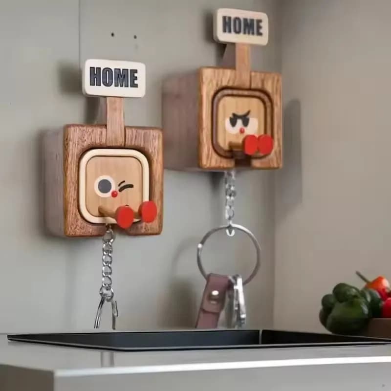 Two artisanal wooden magnetic key racks featuring funny winking and grumpy facial patterns mounted on a wall.