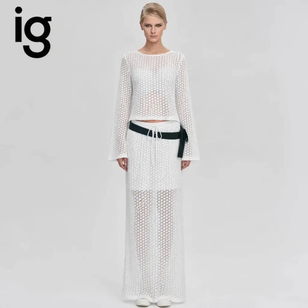 Model wearing a white hollow out knit two-piece set with flare sleeves and a matching maxi skirt.