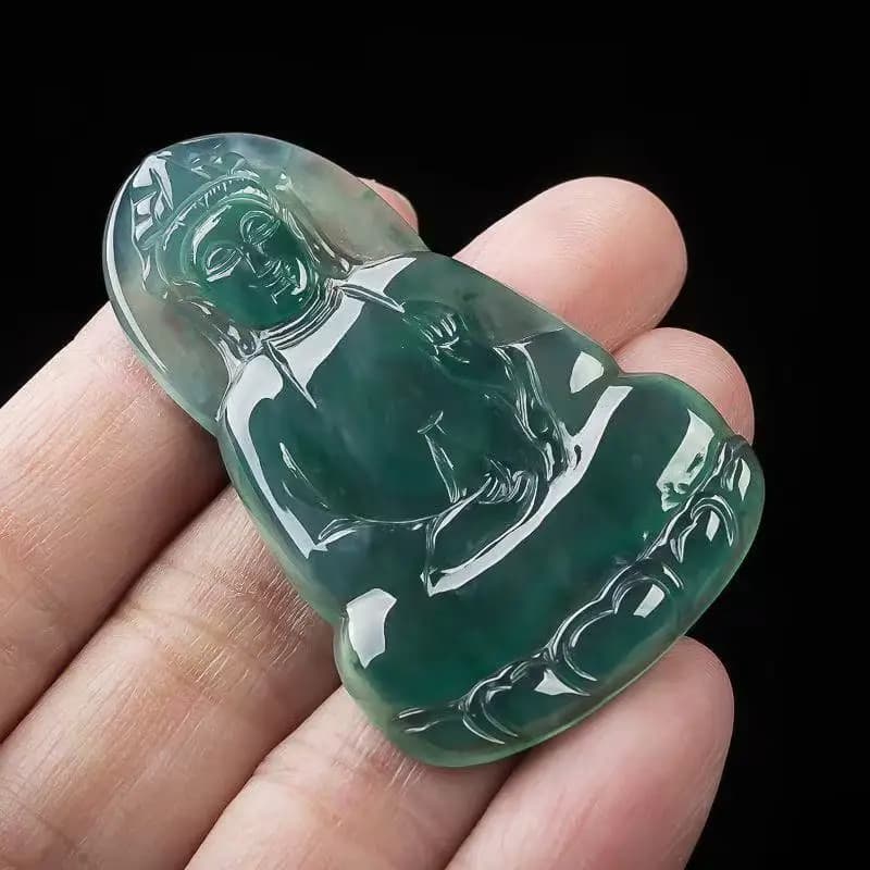 A translucent blue water Burmese jadeite pendant carved in the shape of Guanyin held between fingers.