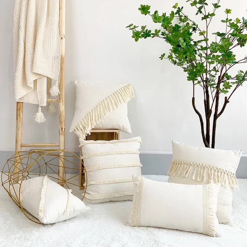 Beige boho-style linen cotton pillow covers with tassel fringe details arranged in a home setting.